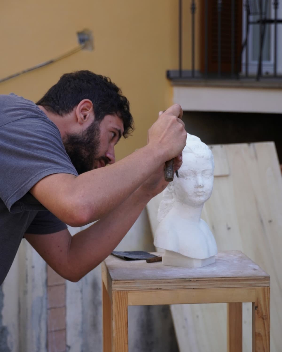 Sculptor concentrating on a plaster bust in a workshop